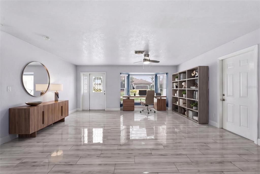 A bright home office features light wood-look tile flooring, a desk, and a large bookshelf — 4431 SE 19TH AVENUE, CAPE CORAL, FL