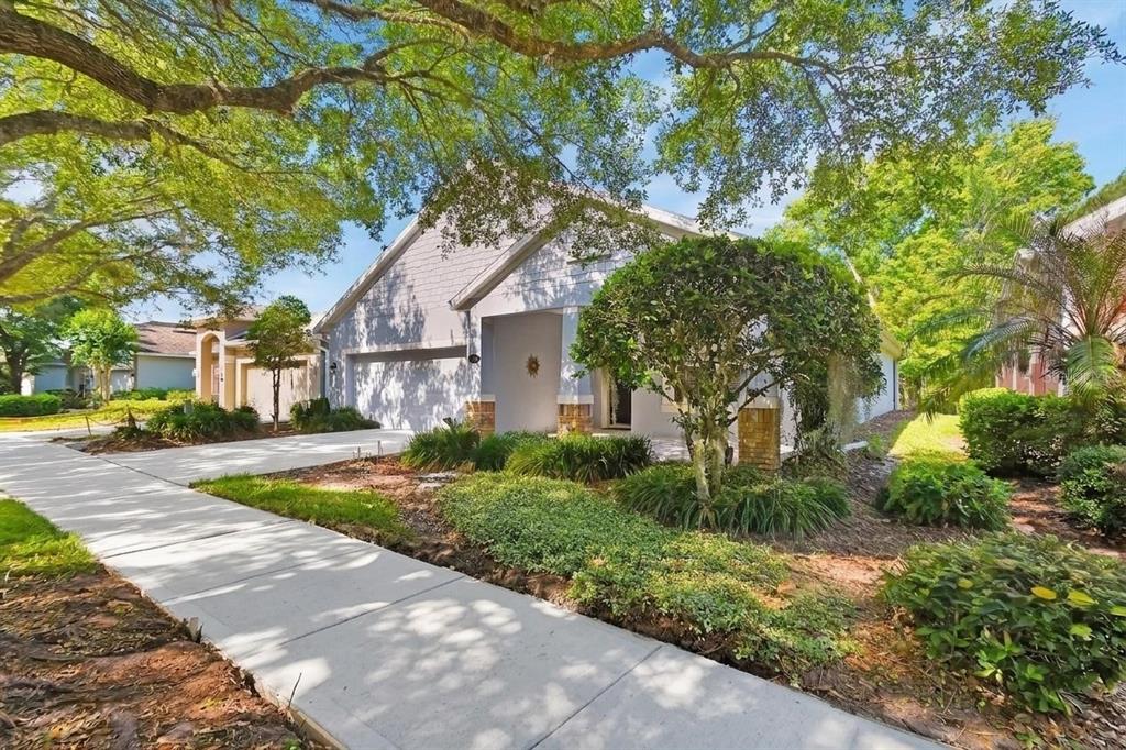 A light-colored single-story house with a two-car garage, a concrete driveway, and mature landscaping — 525 HERON POINT WAY, DELAND, FL