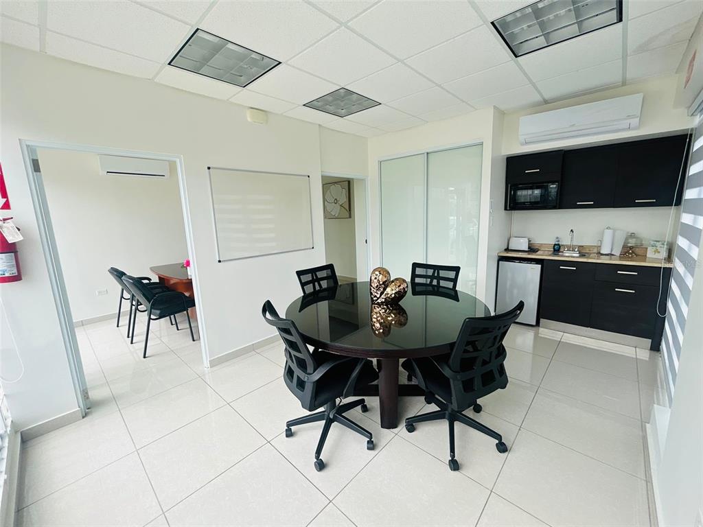 A modern office space features a round table, black chairs, and a small kitchenette — 1396 CALLE BONITA, PONCE, PR