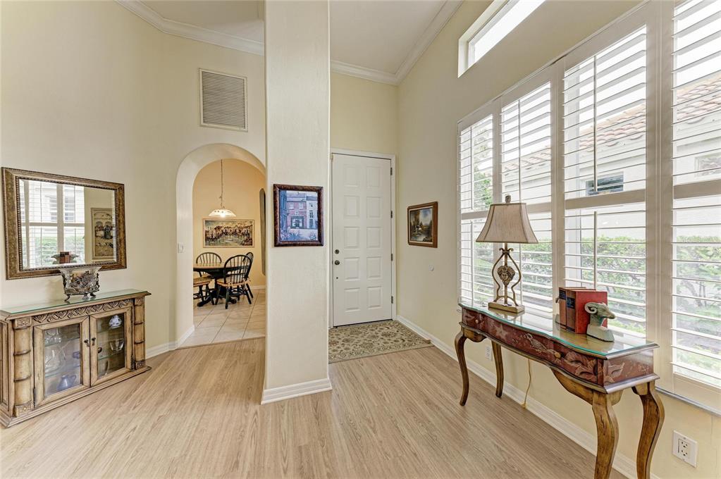 A bright entryway features light wood-look flooring, a white front door, and two console tables — 3883 ALAMANDA DRIVE, SARASOTA, FL