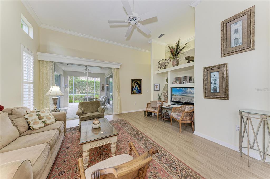 A living room features a beige sofa, a patterned rug, and a built-in media center — 3883 ALAMANDA DRIVE, SARASOTA, FL