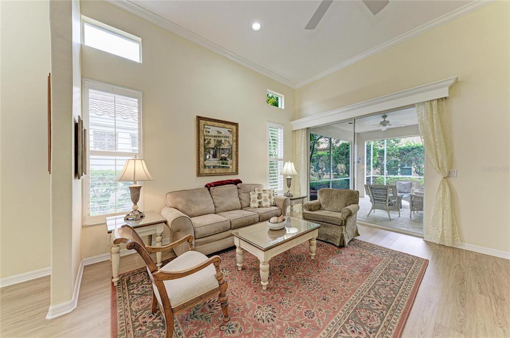 A living room with a sofa, armchairs, a coffee table, and a sliding glass door — 3883 ALAMANDA DRIVE, SARASOTA, FL
