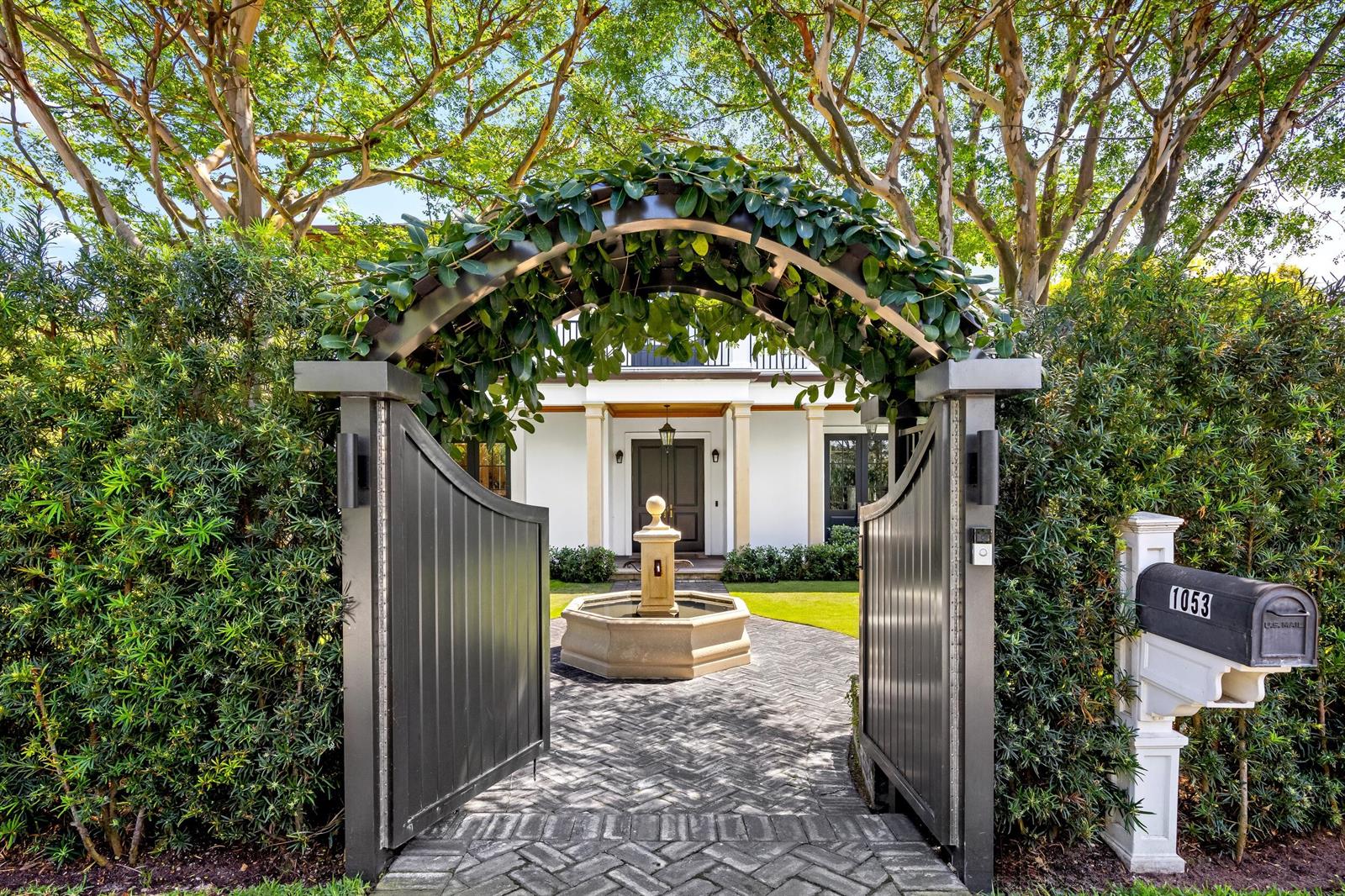 A stone fountain sits on a herringbone brick path leading to a house through gates — 1053 N Lake Way, Palm Beach FL 33480, PALM BEACH, FL