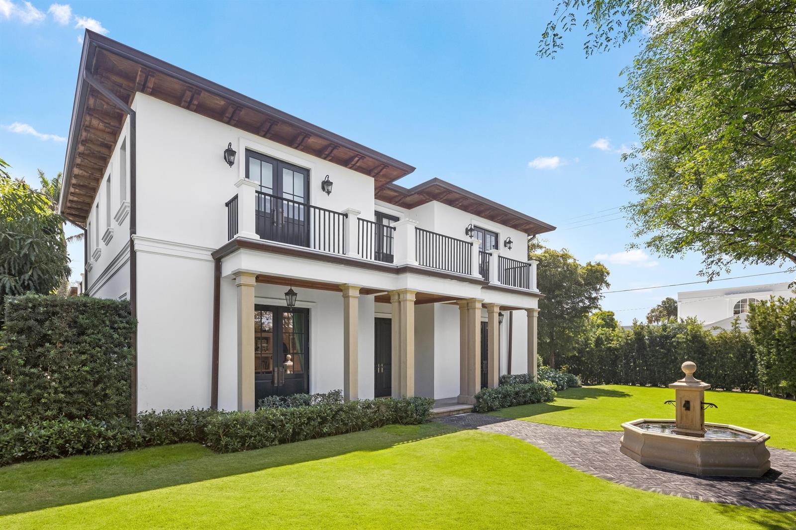 A two-story white house with a balcony, columns, and a stone fountain in the yard — 1053 N Lake Way, Palm Beach FL 33480, PALM BEACH, FL