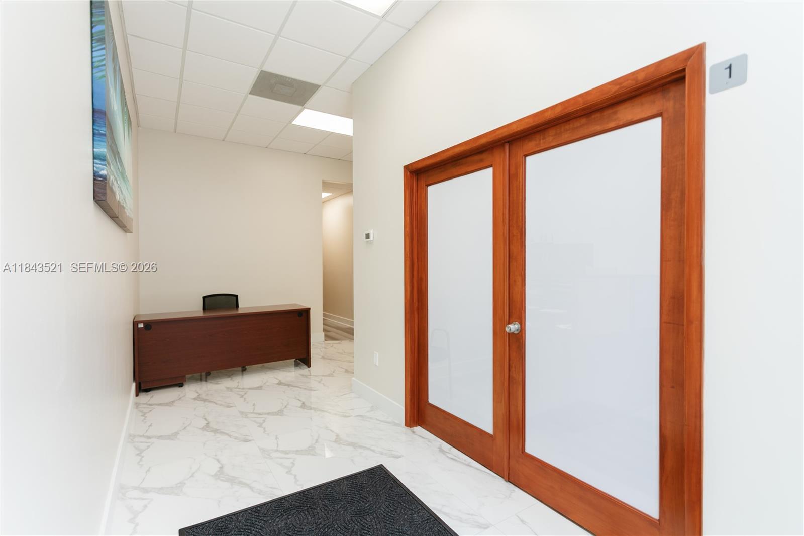 A hallway features white marble-look tile flooring, a dark wood desk, and double glass doors — 1911 Harrison St # 7, Hollywood FL 33020, HOLLYWOOD, FL