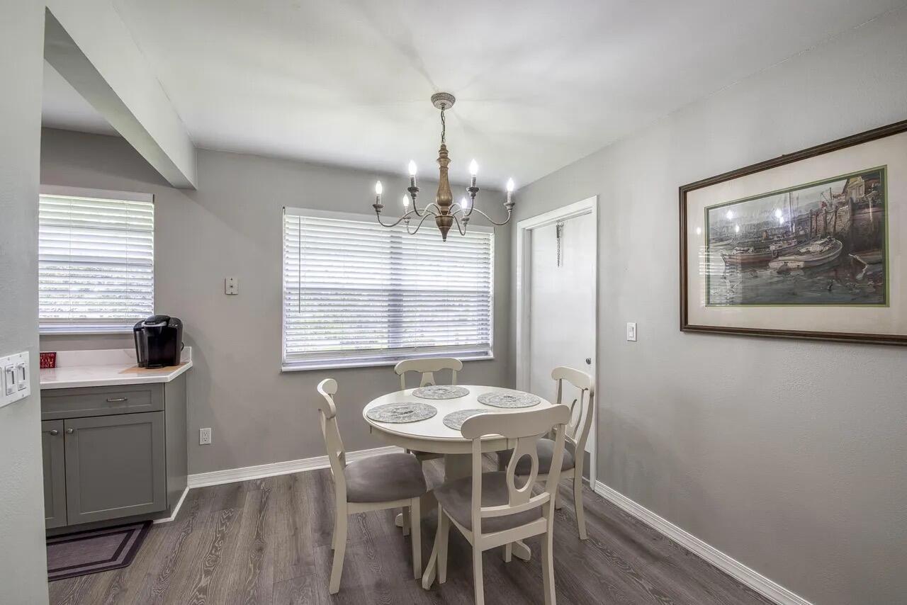 A dining area features a round white table, four chairs, and a chandelier on gray flooring — 2929 SE Ocean Boulevard # 6, Stuart FL 34996, STUART, FL