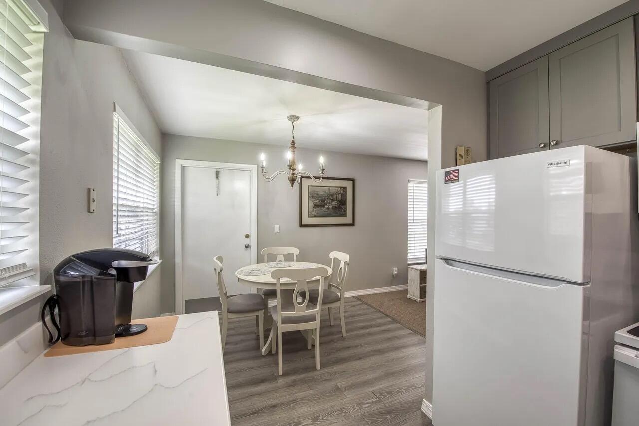 A kitchen and dining area with gray wood-look flooring, white cabinets, and a white refrigerator — 2929 SE Ocean Boulevard # 6, Stuart FL 34996, STUART, FL