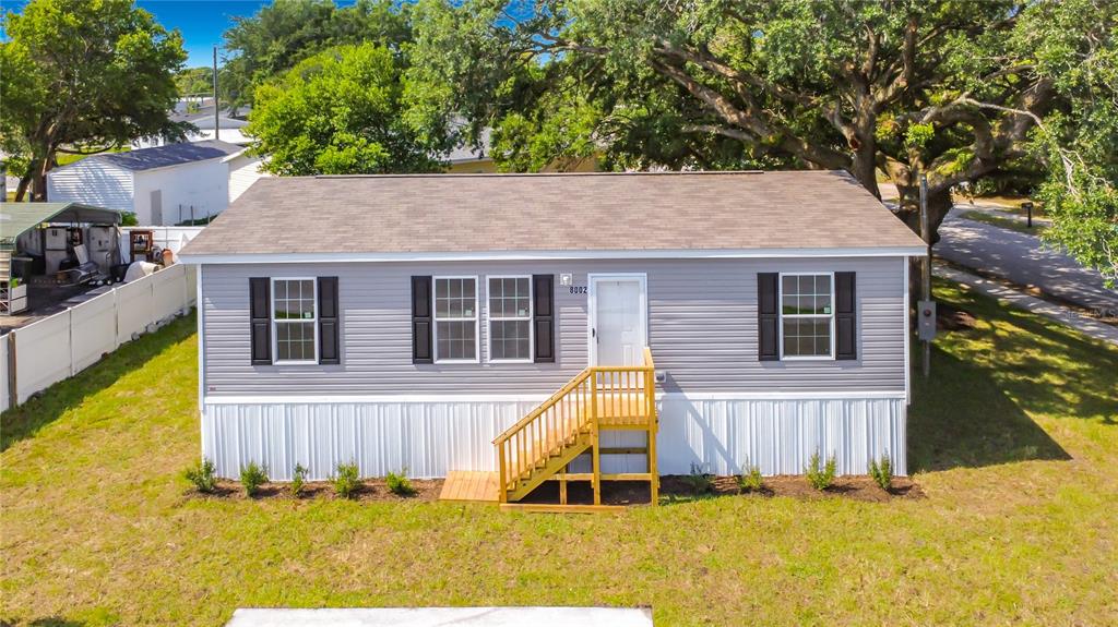 A single-story house with grey vinyl siding, black shutters, and a wooden front staircase — 8002 MOBILAIRE DRIVE, ORLANDO, FL