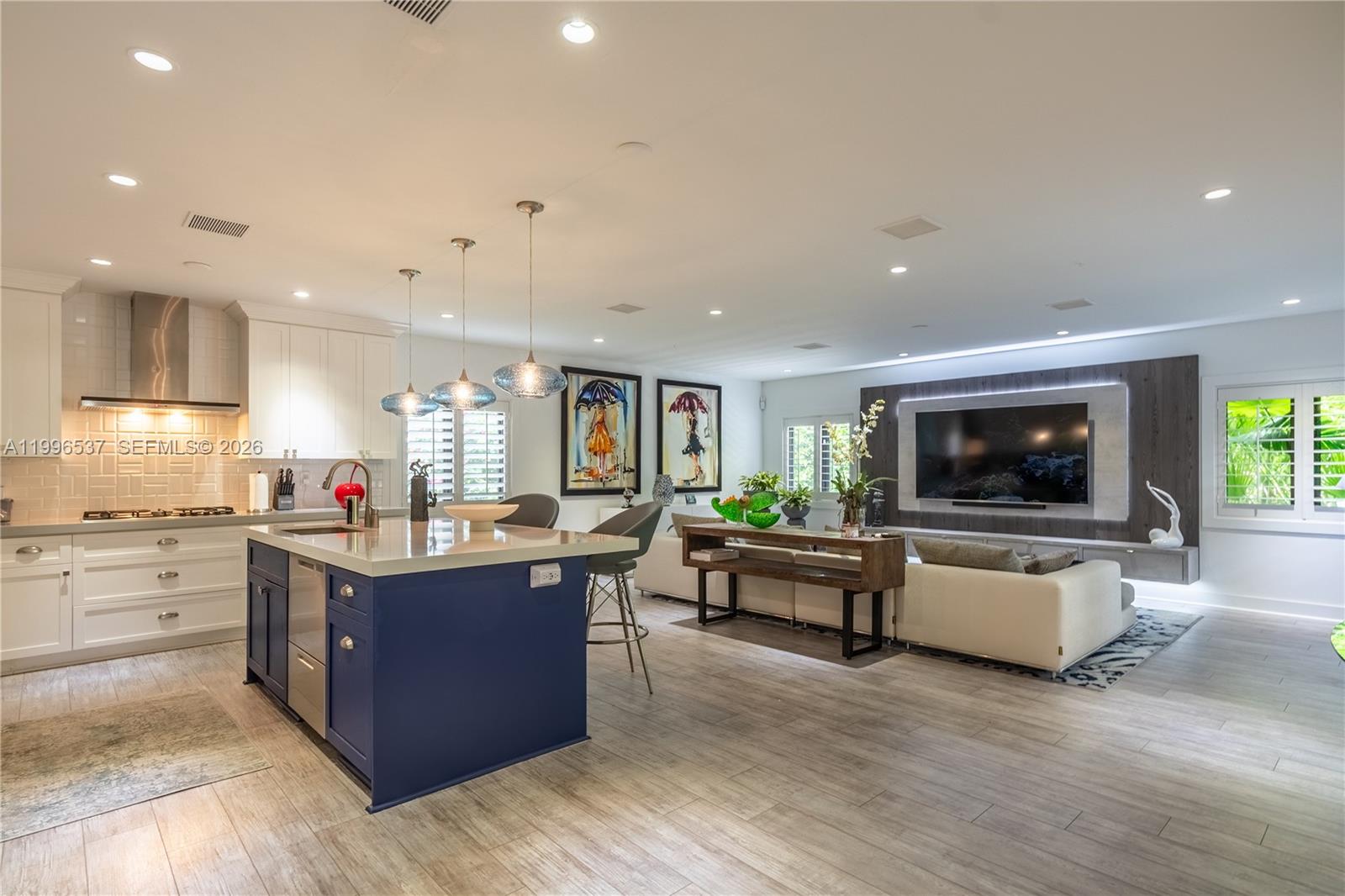 An open-concept kitchen and living area features a blue island, white cabinetry, and a television — 231 Fluvia Ave # 0, Coral Gables FL 33134, CORAL GABLES, FL