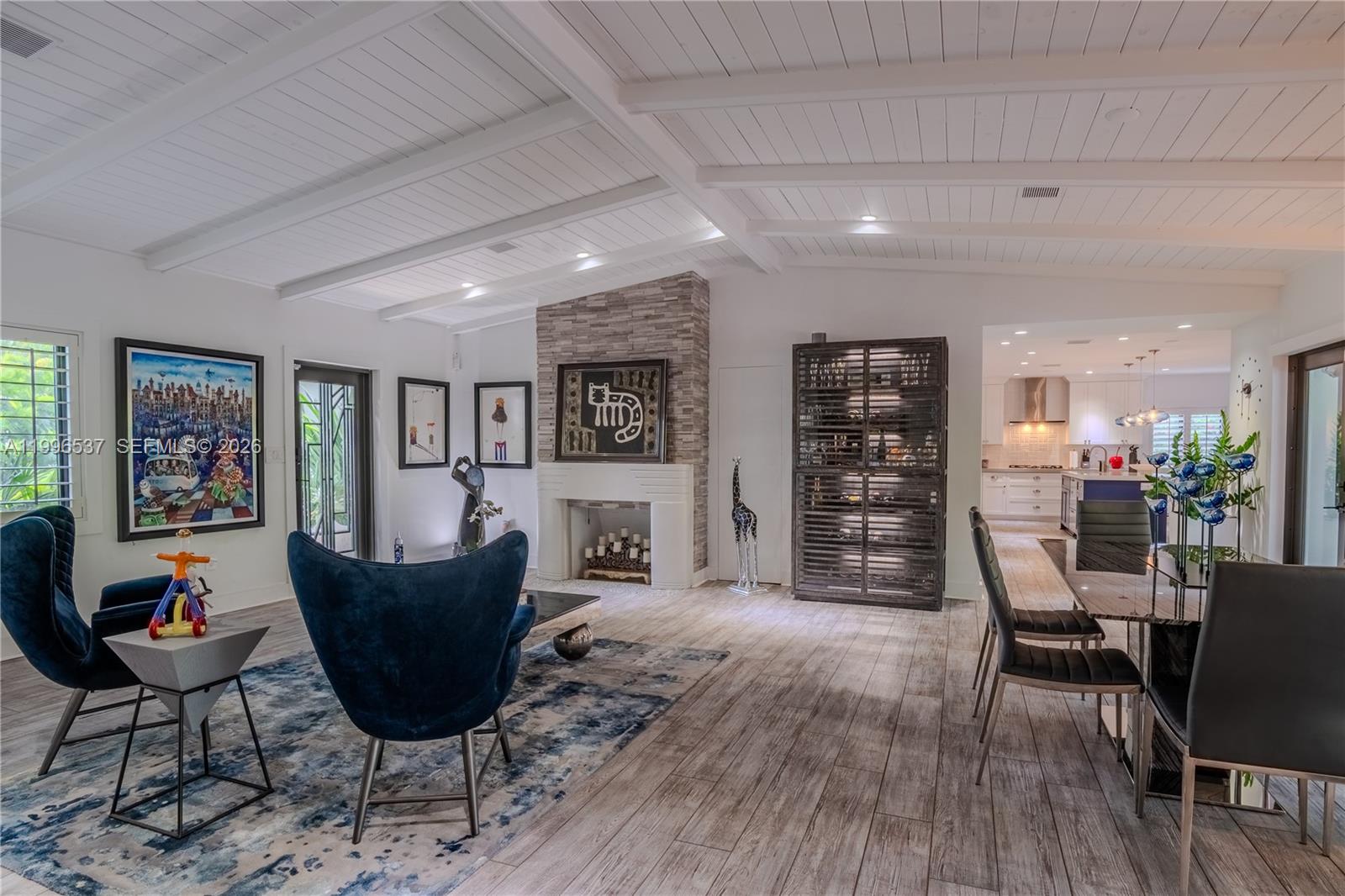 A living and dining area features a stone fireplace, wood-plank flooring, and vaulted ceilings — 231 Fluvia Ave # 0, Coral Gables FL 33134, CORAL GABLES, FL