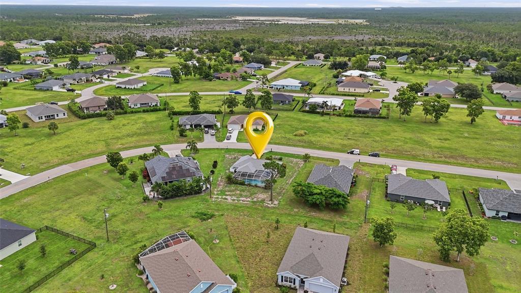 An aerial view shows a single-family house with a pool cage in a suburban neighborhood — 25449 DOREDO DRIVE, PUNTA GORDA, FL