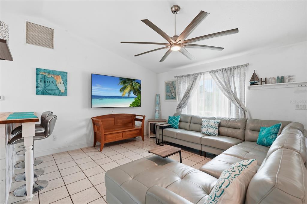 A living room features a large sectional sofa, a wall-mounted television, and a ceiling fan — 25449 DOREDO DRIVE, PUNTA GORDA, FL