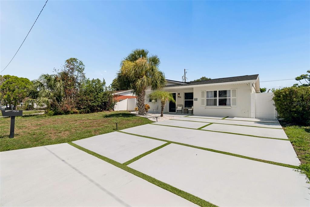 A single-story house with a white exterior and a modern concrete driveway with grass strips — 7508 W CARACAS STREET, TAMPA, FL