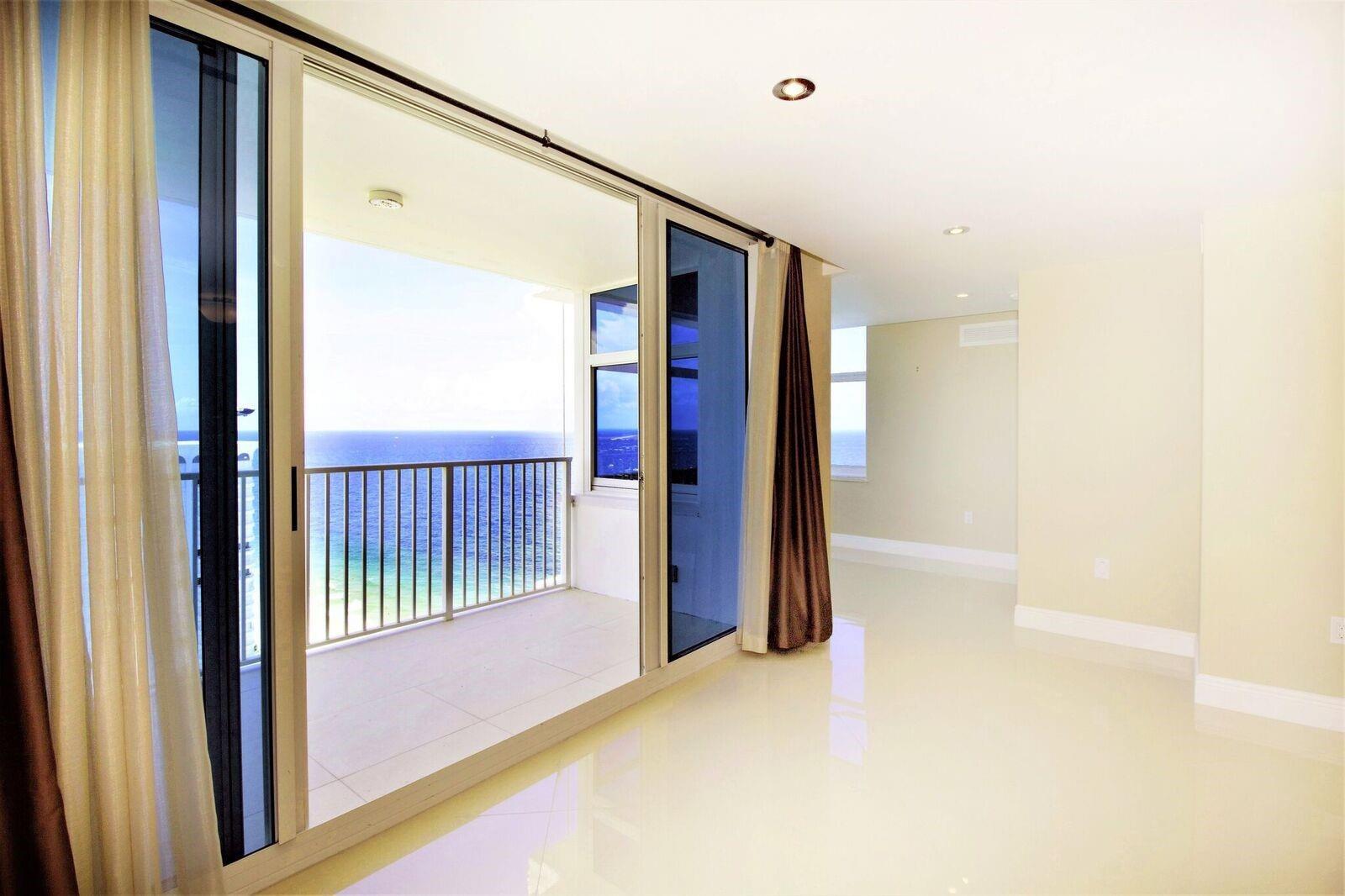 An empty room with white tile floors leads to a balcony overlooking the ocean — 1360 S Ocean Boulevard # 2806, Pompano Beach FL 33062, POMPANO BEACH, FL