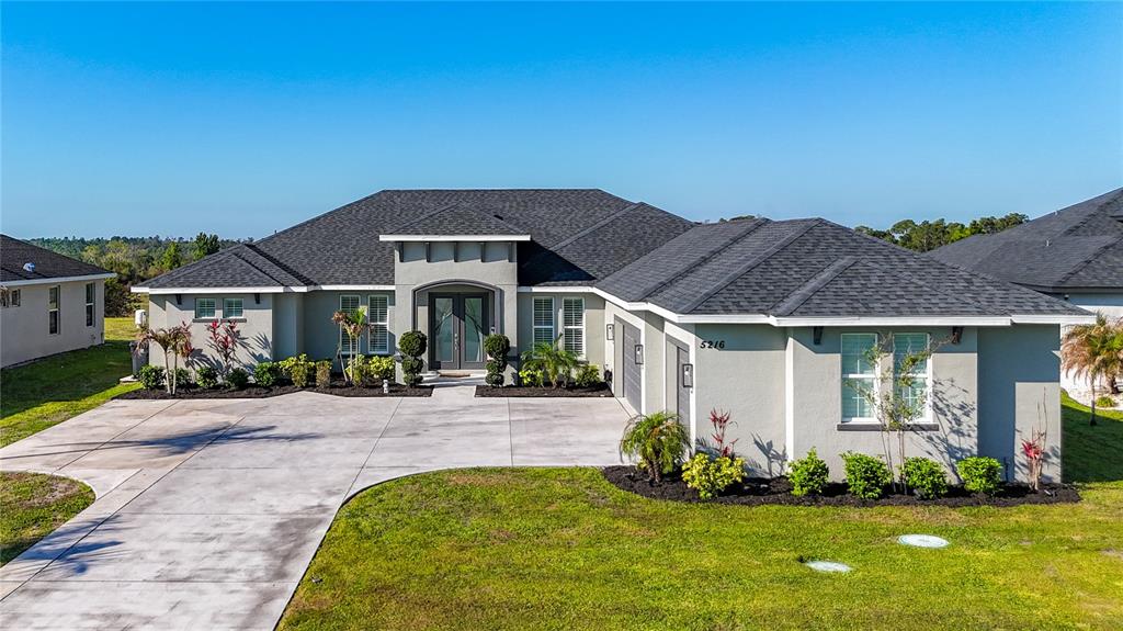A single-story house with a gray stucco exterior, a dark shingled roof, and a concrete driveway — 5216 LAKE VENICE DRIVE, WIMAUMA, FL