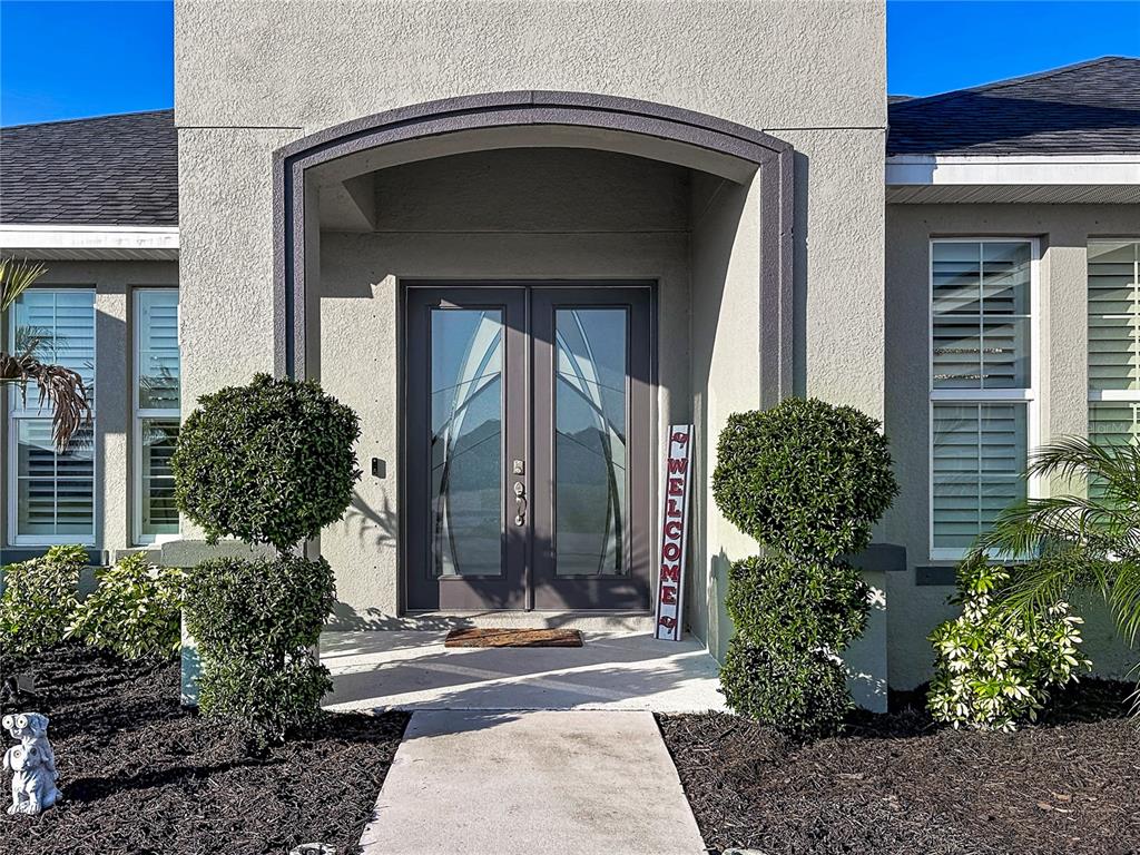 The exterior of a house features a double front door under a recessed arched entryway — 5216 LAKE VENICE DRIVE, WIMAUMA, FL