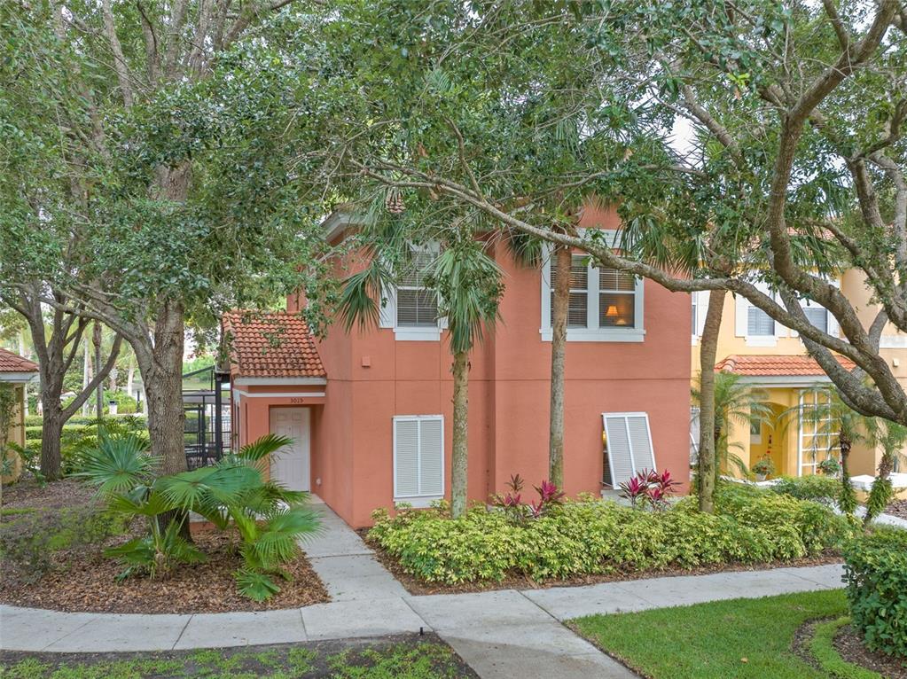 A two-story orange stucco townhouse with a tiled roof and a front walkway — 3015 YELLOW LANTANA LANE, KISSIMMEE, FL