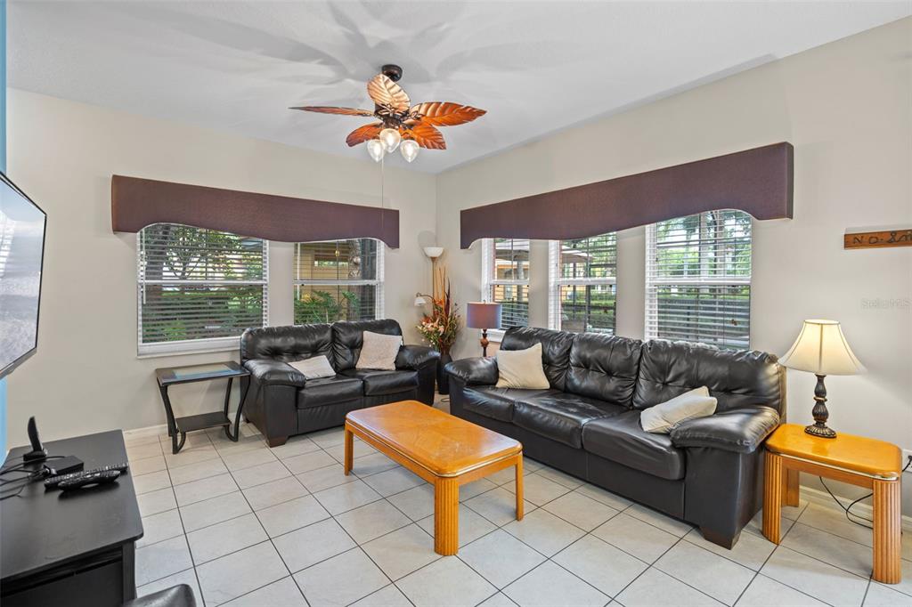 A living room features tile flooring, two black leather sofas, and a wooden coffee table — 3015 YELLOW LANTANA LANE, KISSIMMEE, FL