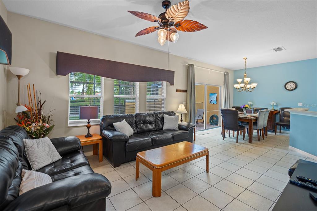 A living room with tile floors, black leather sofas, and an adjacent dining area — 3015 YELLOW LANTANA LANE, KISSIMMEE, FL