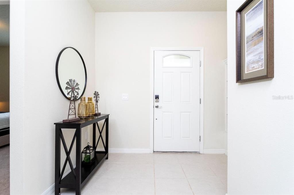 An entryway features a white door, a black console table, and a round wall mirror — 2429 DUBAI STREET, KISSIMMEE, FL