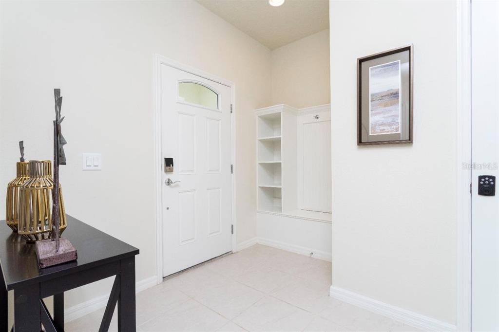 An entryway features a white front door, built-in shelving, tile flooring, and a console table — 2429 DUBAI STREET, KISSIMMEE, FL