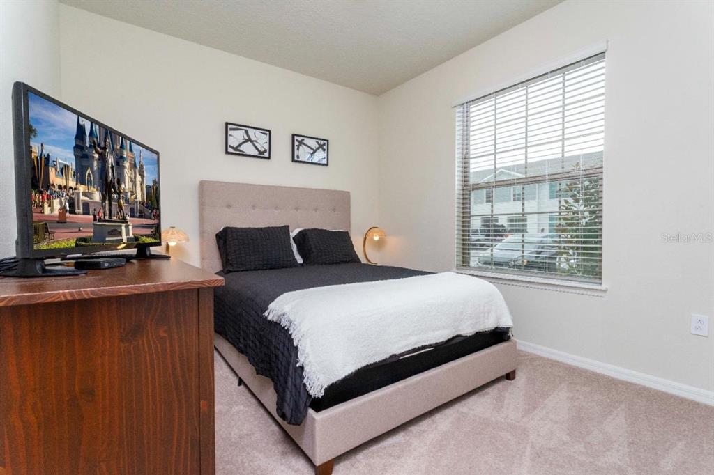 A bedroom features a bed with black bedding, a television, and a window with blinds — 2429 DUBAI STREET, KISSIMMEE, FL