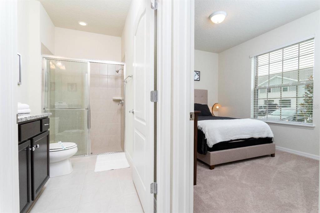 A bathroom with a glass-enclosed shower and a bedroom with a bed are visible — 2429 DUBAI STREET, KISSIMMEE, FL