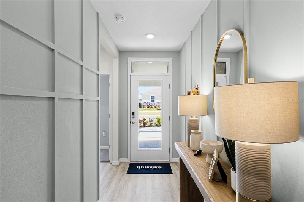 A bright entryway features light wood flooring, board and batten walls, and a glass-paneled door — 7851 FORREST FOX WAY, LAKELAND, FL