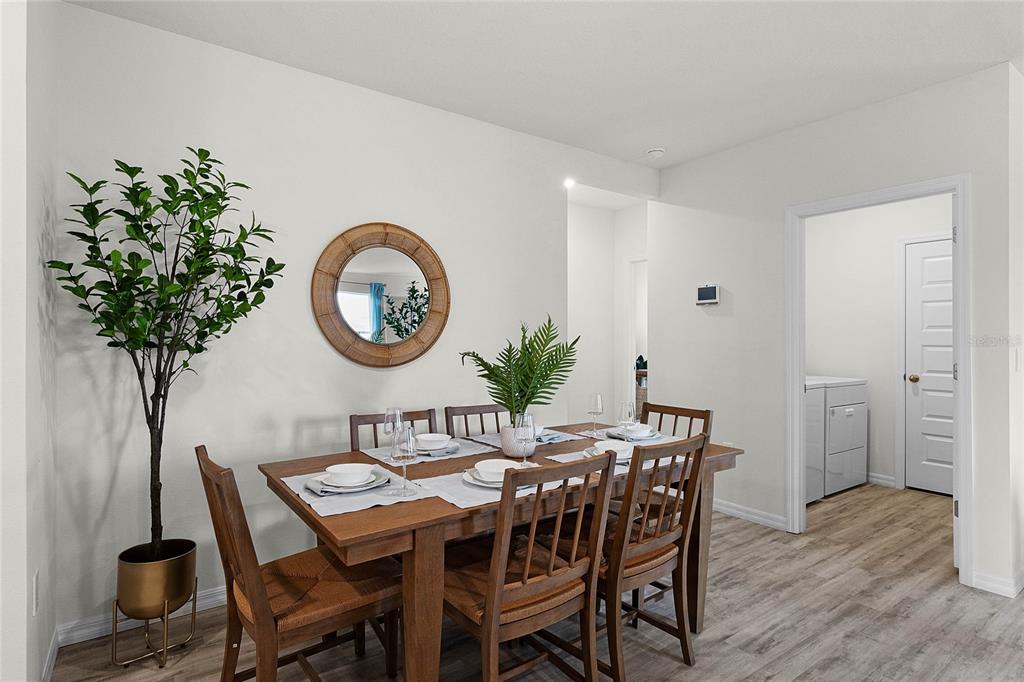 A dining room features a wooden table with four chairs, a round mirror, and wood-look flooring — 7851 FORREST FOX WAY, LAKELAND, FL