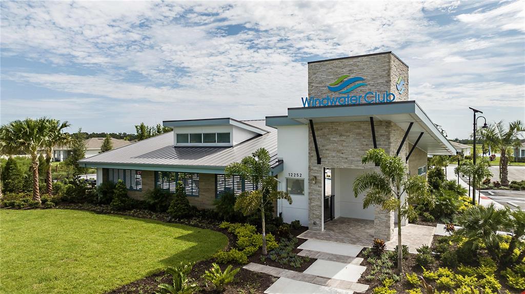 The exterior of a modern clubhouse features stone accents, a metal roof, and palm trees — 12447 49TH STREET E, PARRISH, FL
