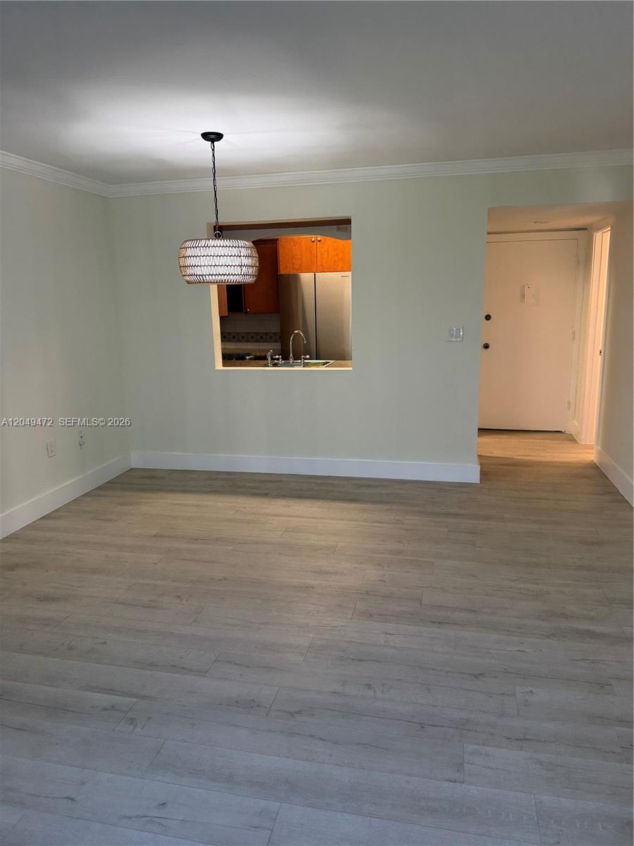 A dining area with light wood-look flooring features a pendant light and a kitchen pass-through — 7403 SW 82nd St # 109N, Miami FL 33143, MIAMI, FL