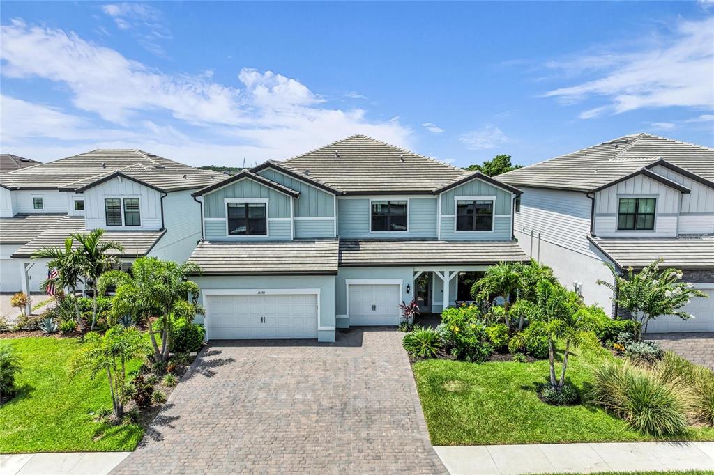 A two-story suburban house with light blue siding, a tiled roof, and a paved driveway — 16438 SLATE PLACE, LAKEWOOD RANCH, FL