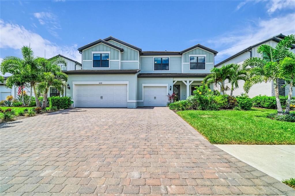A two-story house with light blue siding, a paver driveway, and a three-car garage — 16438 SLATE PLACE, LAKEWOOD RANCH, FL
