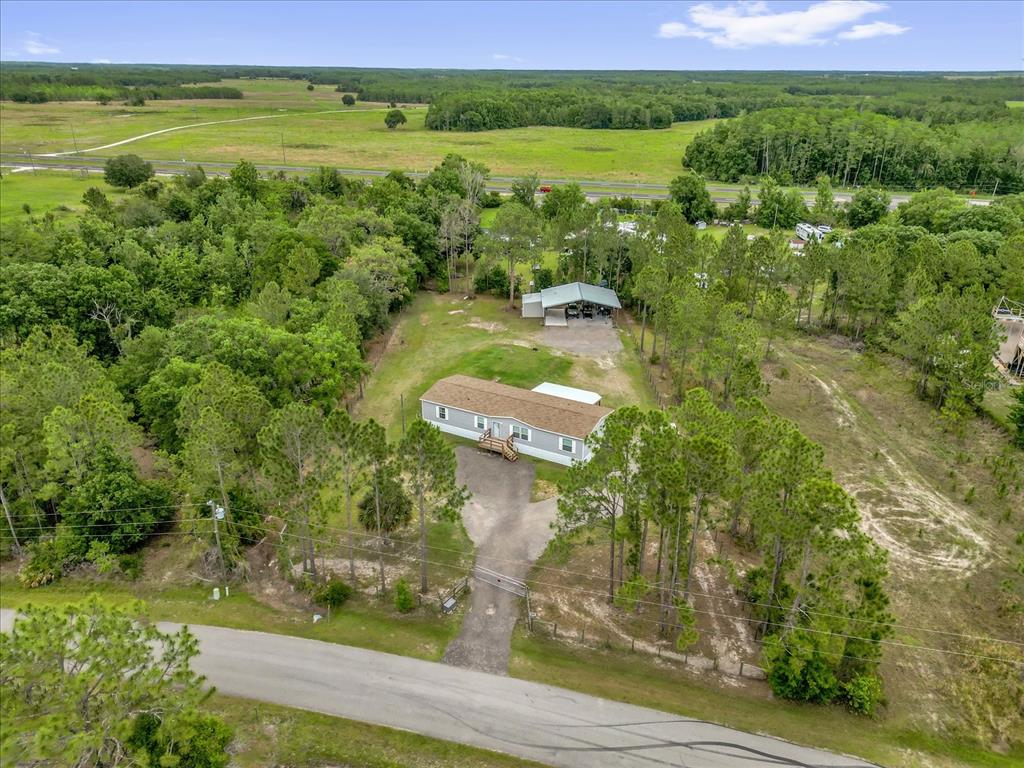 An aerial view shows a single-story house and a detached garage on a wooded lot — 9165 LUNA DRIVE, ST CLOUD, FL