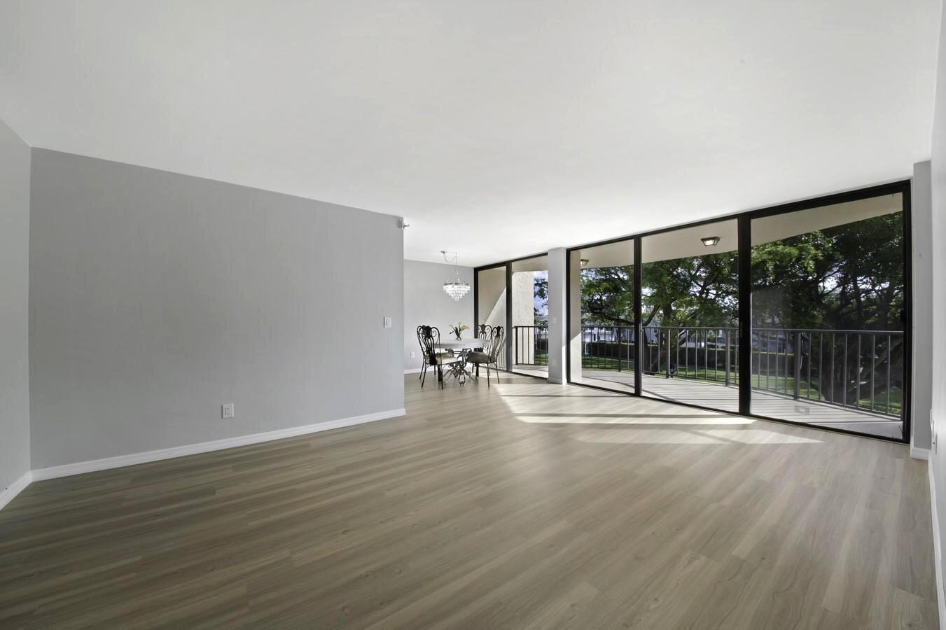 An empty living room with light gray walls, wood-look flooring, and large sliding glass balcony doors — 859 Jeffery Street # 311, Boca Raton FL 33487, BOCA RATON, FL