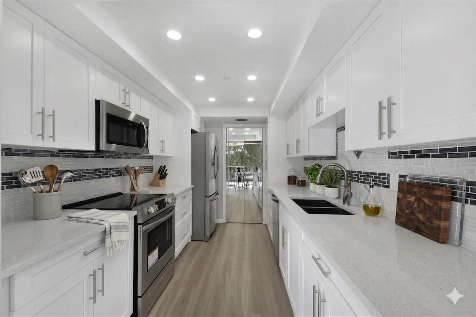 A galley kitchen features white cabinets, stainless steel appliances, quartz countertops, and a tiled backsplash — 859 Jeffery Street # 311, Boca Raton FL 33487, BOCA RATON, FL