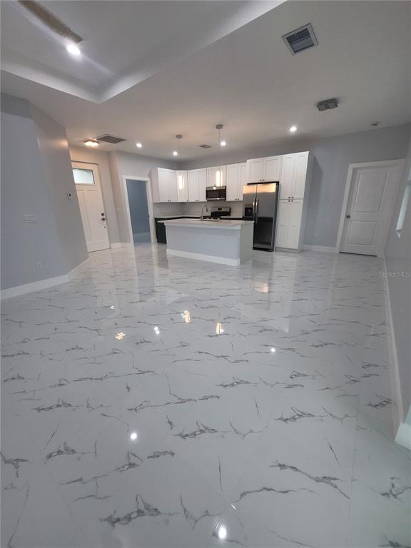 A kitchen with white cabinets, a central island, and polished marble-look tile flooring — 12025 CLARENDON AVENUE, PORT CHARLOTTE, FL
