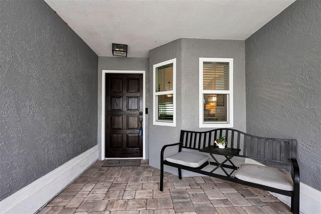 A covered entryway features a dark wood door, two windows, and a metal bench — 11916 SNAPDRAGON ROAD, TAMPA, FL