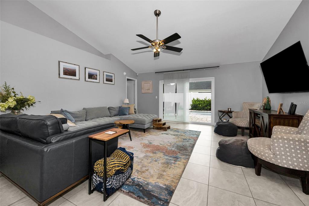 A living room features a gray sectional sofa, patterned area rug, and a ceiling fan — 11916 SNAPDRAGON ROAD, TAMPA, FL