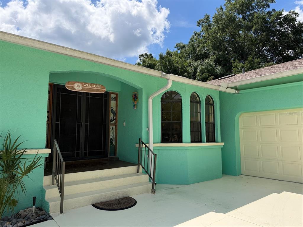 A mint green house exterior features an arched entryway, a garage, and three arched windows — 11878 W RIVERHAVEN DRIVE, HOMOSASSA, FL