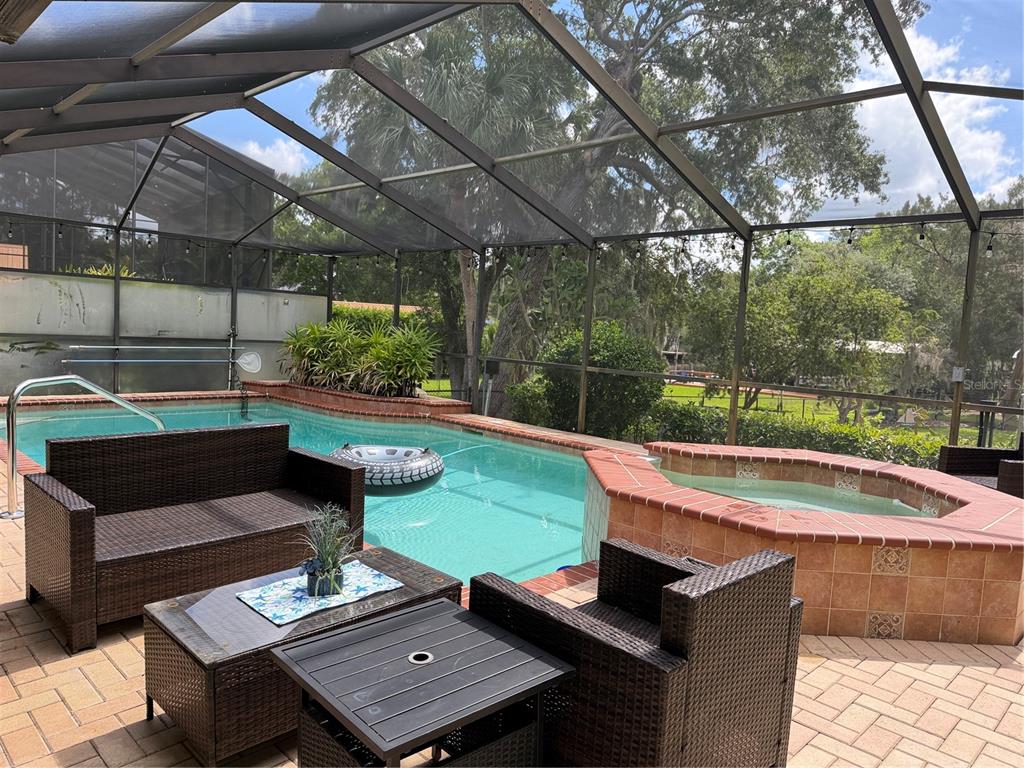 A screened-in patio features a swimming pool, a raised hot tub, and wicker outdoor furniture — 11878 W RIVERHAVEN DRIVE, HOMOSASSA, FL