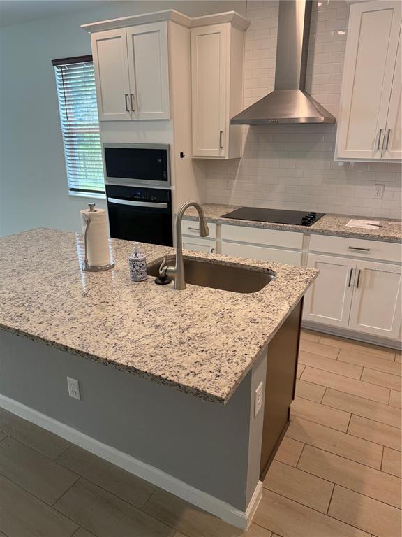 A kitchen features a granite-topped island with a sink, white cabinets, and stainless steel appliances — 5089 GRAND TETON COURT, DELAND, FL