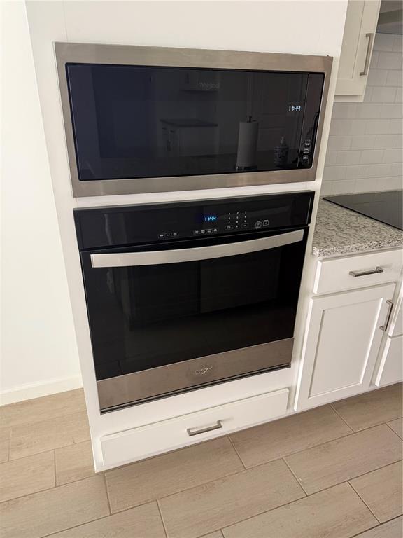 A built-in Whirlpool microwave and oven unit are set into white cabinetry in a kitchen — 5089 GRAND TETON COURT, DELAND, FL