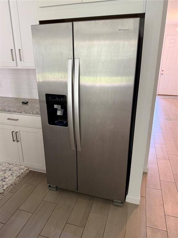 A stainless steel Whirlpool side-by-side refrigerator is positioned in a kitchen with white cabinets — 5089 GRAND TETON COURT, DELAND, FL