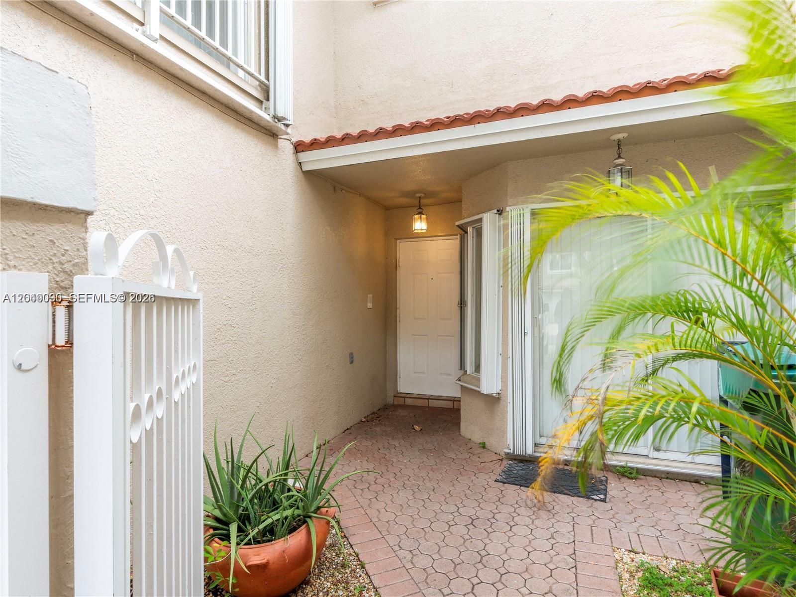 A paved entryway leads to a white front door and a sliding glass door — 5243 NW 102nd Ct # 5243, Doral FL 33178, DORAL, FL