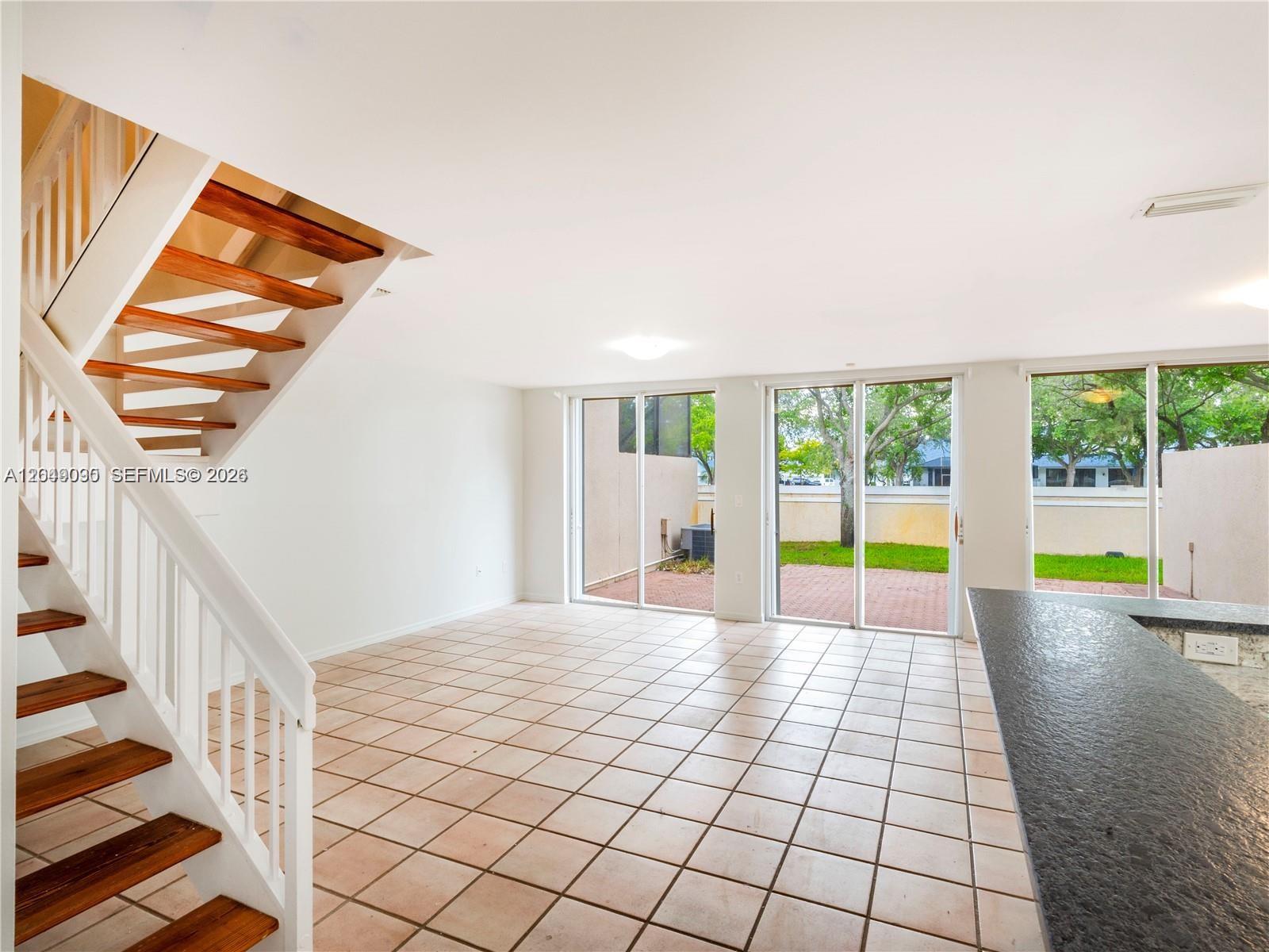 An open living area features tile flooring, a wooden staircase, and sliding glass doors — 5243 NW 102nd Ct # 5243, Doral FL 33178, DORAL, FL