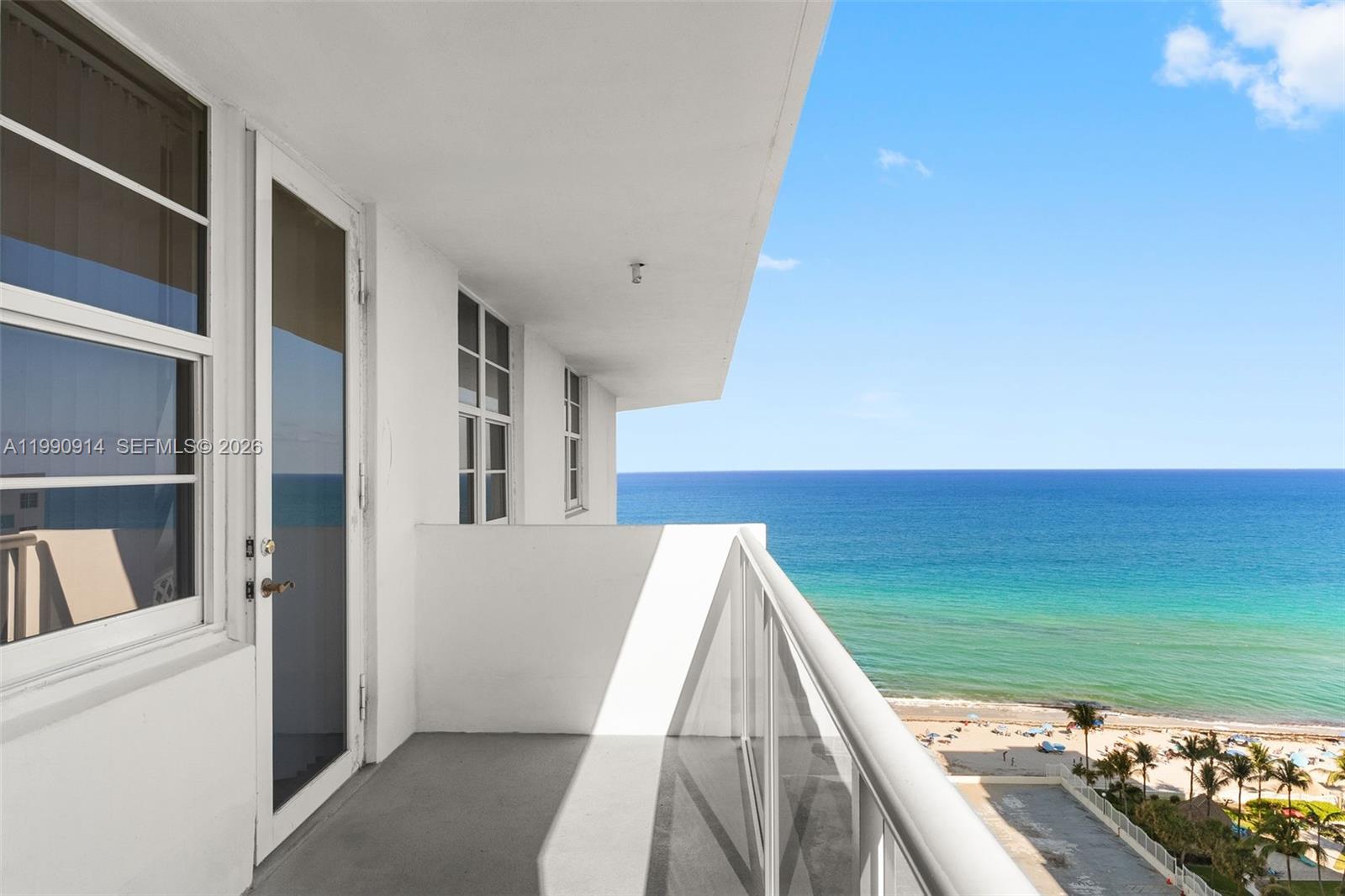 A balcony with a glass railing overlooks the ocean and a sandy beach — 3725 S Ocean Dr, Hollywood FL 33019, HOLLYWOOD, FL