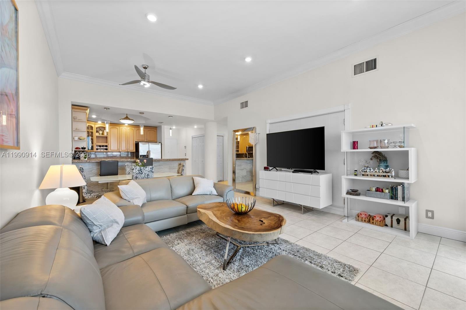 A living room features a grey sectional sofa, live-edge coffee table, and white shelving unit — 3725 S Ocean Dr, Hollywood FL 33019, HOLLYWOOD, FL