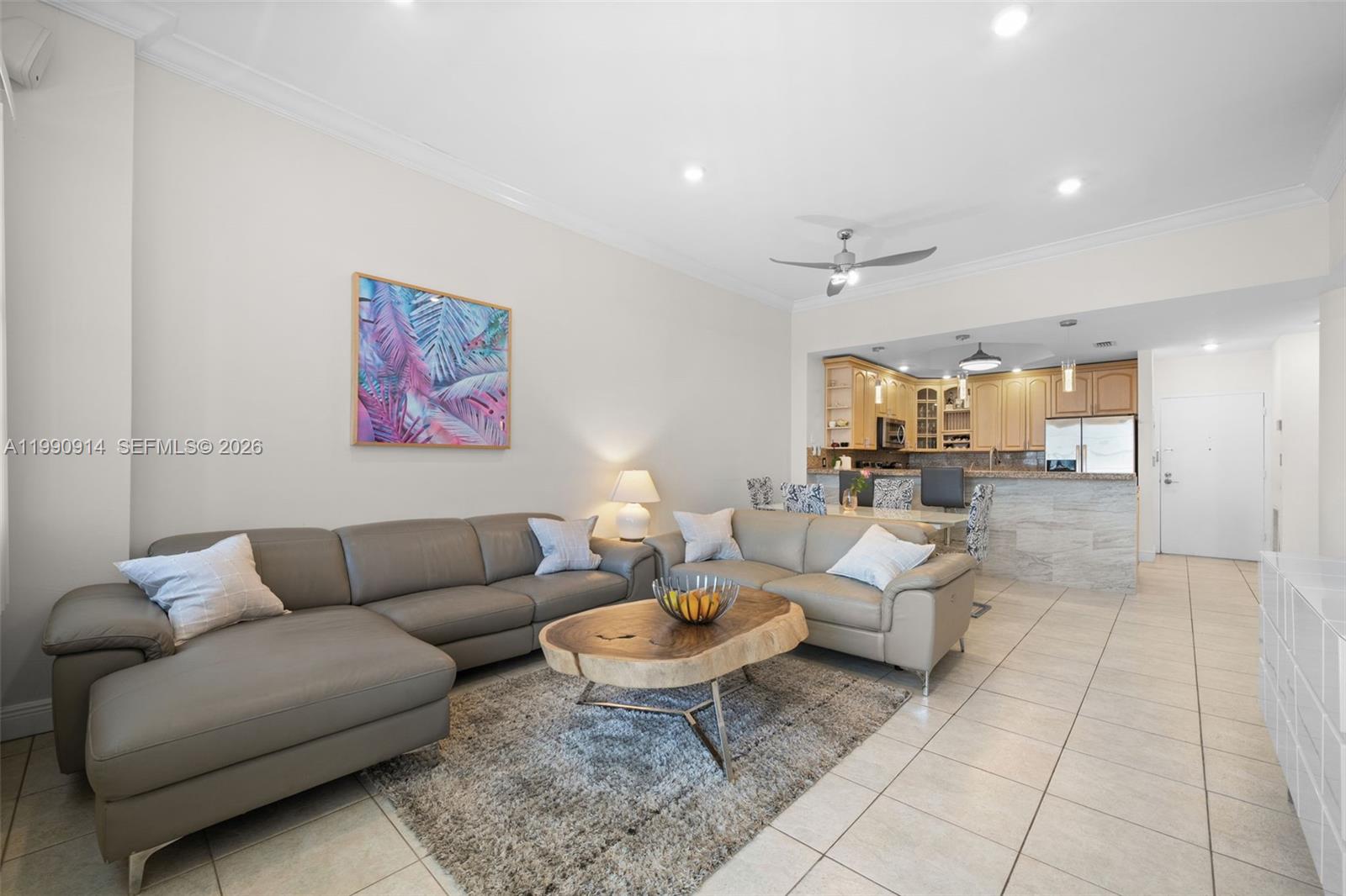 A living room with a gray sectional sofa, live-edge coffee table, and open-concept kitchen — 3725 S Ocean Dr, Hollywood FL 33019, HOLLYWOOD, FL