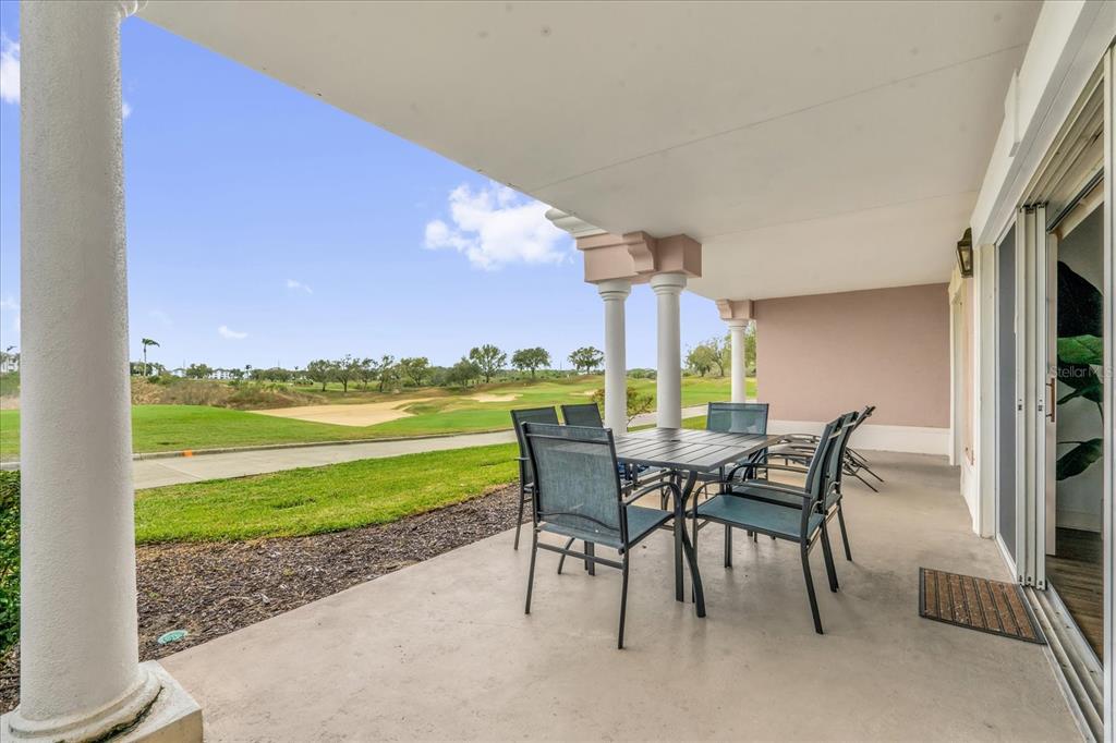 A covered patio with outdoor dining furniture overlooks a golf course — 1362 CENTRE COURT RIDGE DRIVE UNIT 102, REUNION, FL